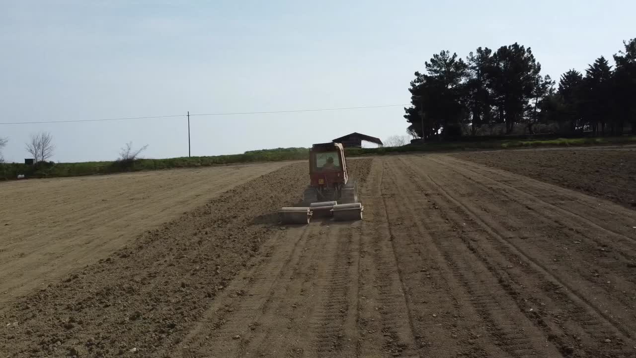 red tractor prepare the land before seeding, aerial footage of agricultural farming