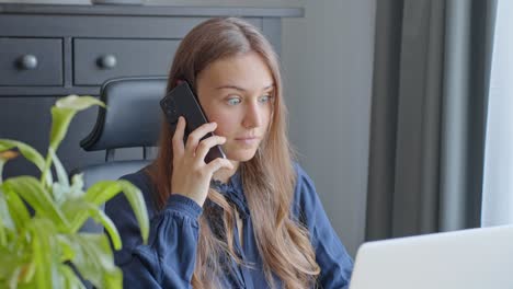 joven trabajadora de oficina en una llamada telefónica conmocionada al oír noticias de trabajo