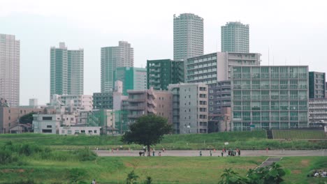 japanese children playing at the park in tamagawa with high rise buildings in the background in tokyo, japan - wide shot