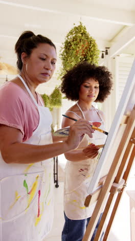 vertical video: painting on canvas, women in aprons creating artwork together in studio