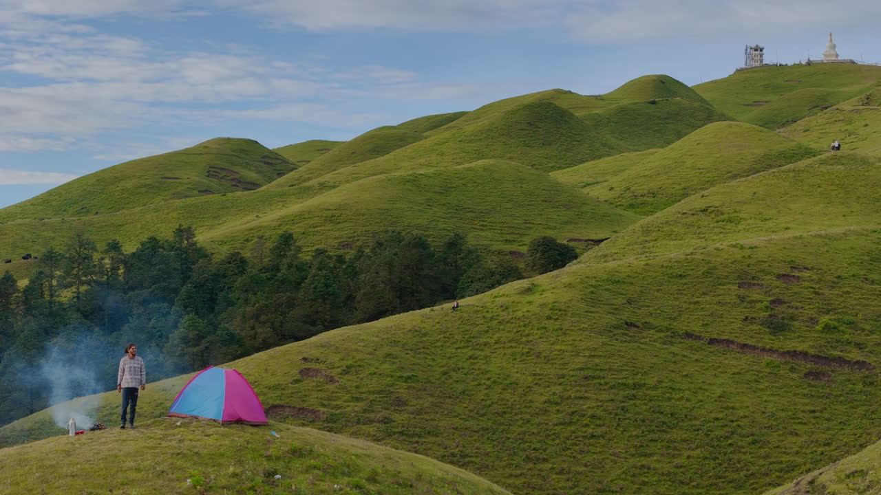 남성 트레커는 티베트 근처의 세일롱, 도라카, 네팔에서 아름다운 풍경에 깨어나 아침에 불꽃 에 앉아 풍요로운 초록색과 조용한 자연 속에서 평화로운 솔로 여행을 즐긴다.