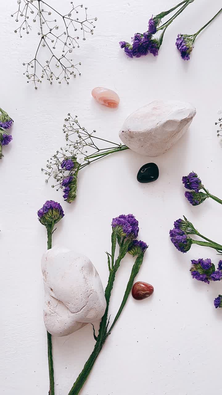 Arrangement med lilla blomster, sten og krystaller