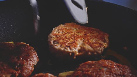 flipping juicy burger patties cooking in a non-stick frying pan