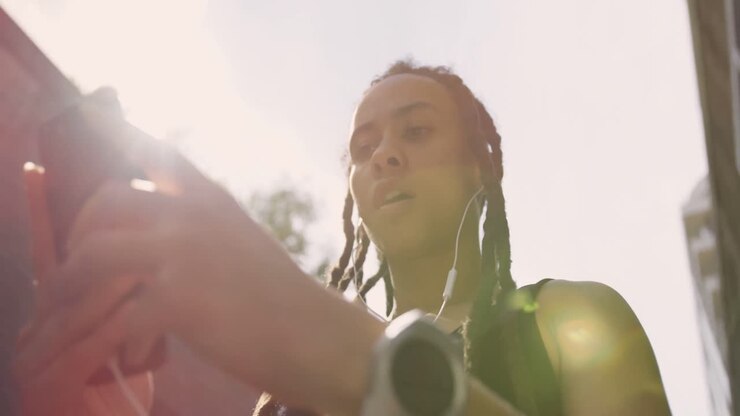 Vista dal basso di giovane donna afroamericana che usa il cellulare in città 4k