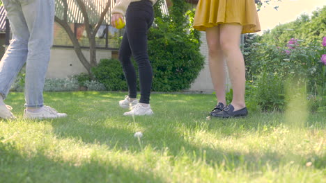 gruppe von frauen und männern, die bunte petanque-bälle aus dem gras nehmen