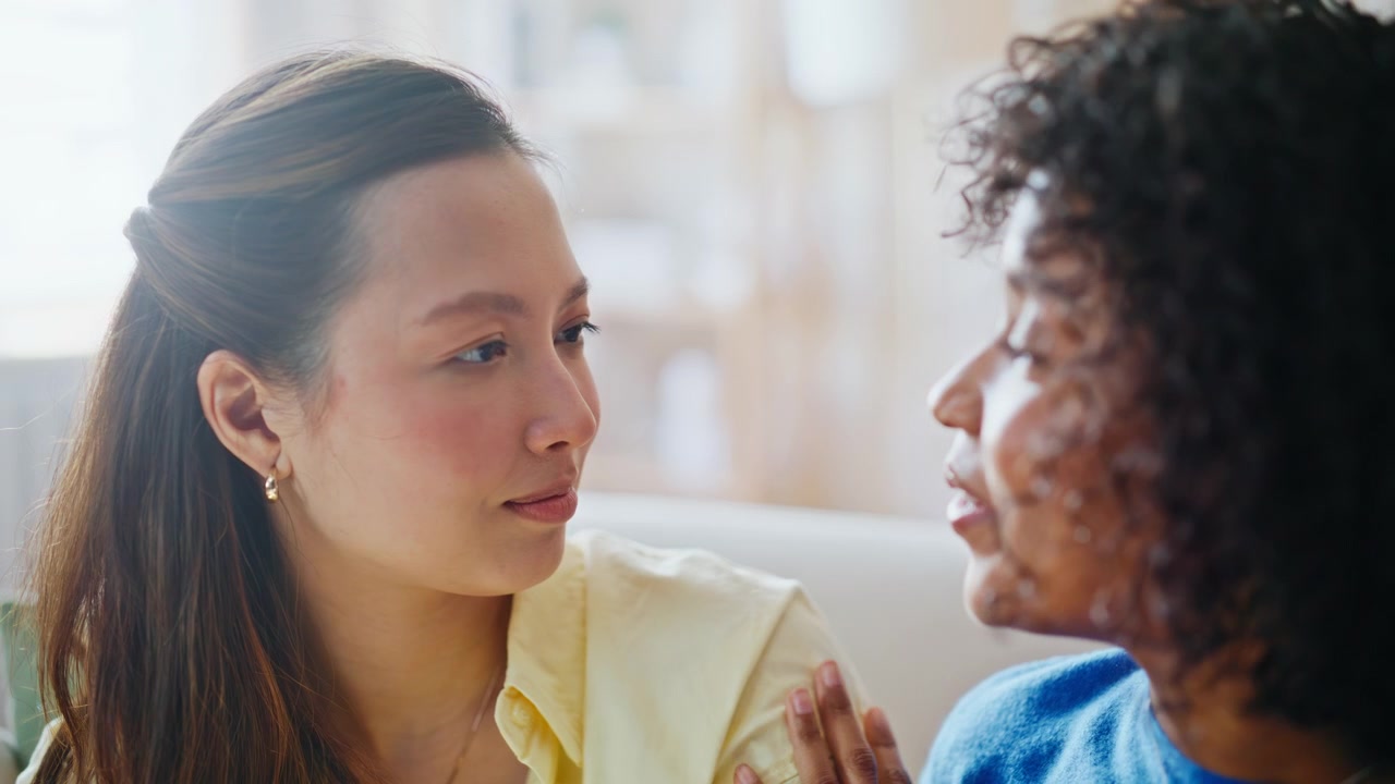 Multiracial couple sharing tender moment sofa. Closeup women talking home.