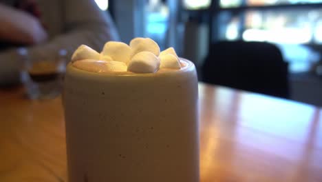 2-3-Bokeh-Hintergrund-Im-Café-Mit-Verschwommenen-Kunden,-Die-Am-Tisch-Sitzen-Und-Espresso-Cappuccino-heiße-Schokolade-Mit-Marshmallows-Auf-Holztisch-Genießen,-Tagsüber-Unkonzentrierte-Leere-Sitze-Dahinter