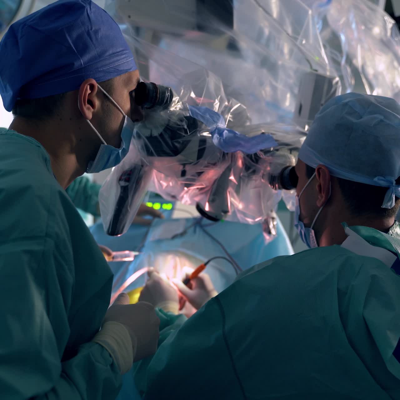 Two professionals operating the patient looking into microscope. Cooperation of surgeons during neurosurgical operation