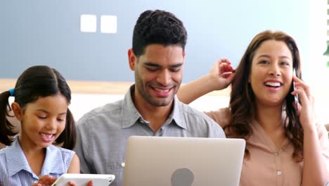 familia feliz usando portátil, teléfono móvil, tableta digital en la sala de estar