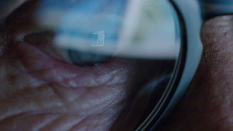 Cerrar-La-Pantalla-Del-Ojo-Macro-Reflejada-En-Las-Gafas-Anciana-Navegando-En-Línea-Por-La-Noche