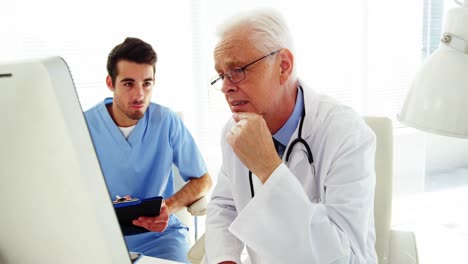 male doctor and coworker discussing over computer