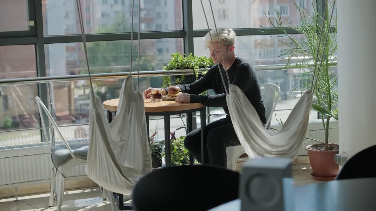 un tipo comiendo una hamburguesa en un restaurante.