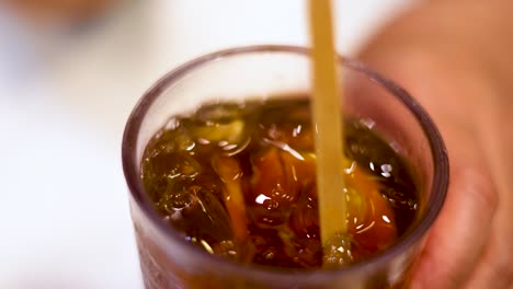 hand stirring iced lemon tea with straw