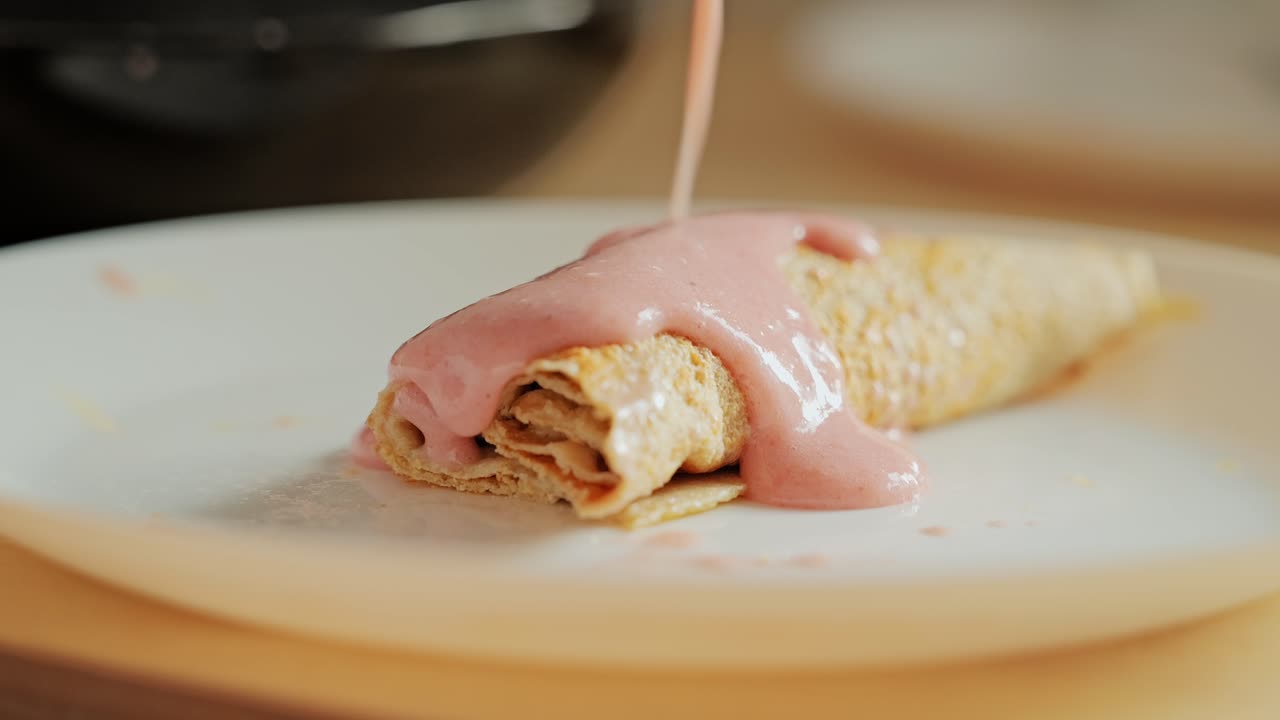 Close up, soft crepe being covered with homemade creamy banana strawberry blend