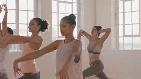 yoga-class-multi-ethnic-women-practicing-warrior-pose-enjoying-healthy-lifestyle-exercising-in-fitness-studio-at-sunrise