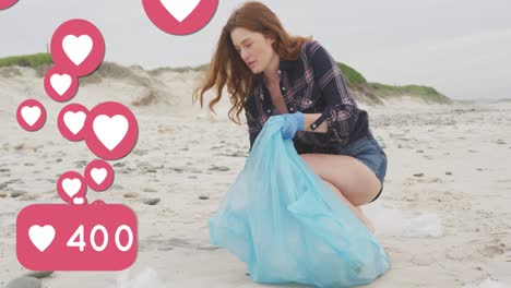 animation of social media heart icons over smiling caucasian woman picking up rubbish from beach