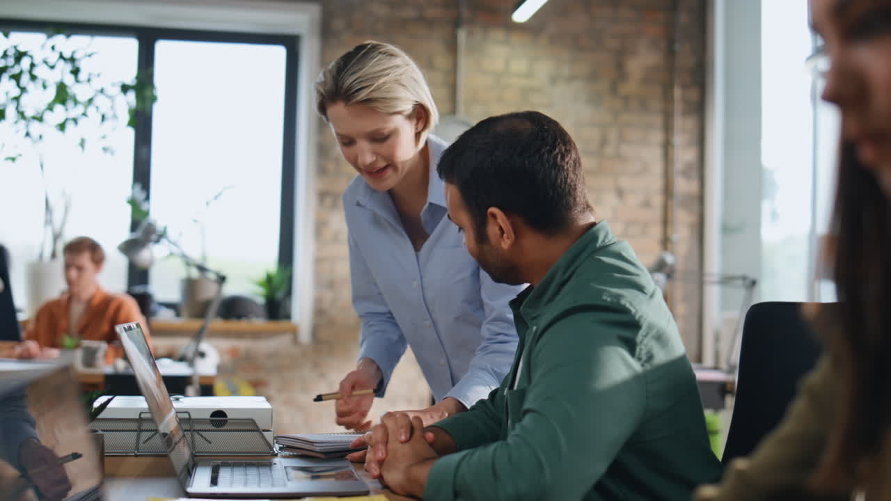 Businesswoman coaching man trainee working office on laptop. Young team interns
