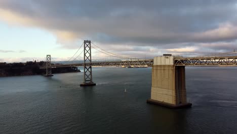 4k 30fps flying up aerial drone footage of san francisco oakland bay bridge double suspension - cars road trip interstate 80, sailboats, stormy cumulus clouds, calm water, sun reflecting off waves