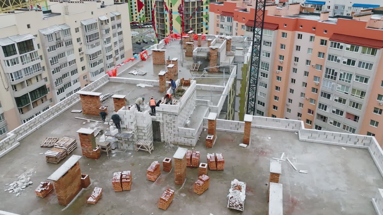Building works on the roof of the apartment block. Building brigade working actively on top of the house. New construction in the residential area.