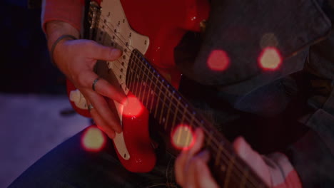 male musician fretting red electric guitar in music studio, overlaying animated sound wave visuals