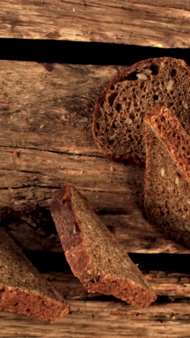 Scheiben dunkles Vollkornbrot mit Körnern auf rustikalem Holztisch