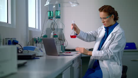 woman scientist studying chemical liquid in lab flask. chemical engineering