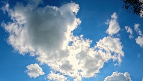 time lapse looking up blue sky with rolling white clouds