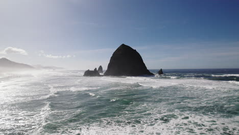 misty mountains and a shadowy haystack rock dominate the coastline view