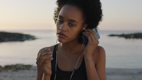 portrait-of-fit-african-american-woman-looking-to-camera-puts-on-earphones-listening-to-music-using-smartphone