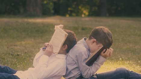 boys with dark hair wearing shirts hold textbooks on face