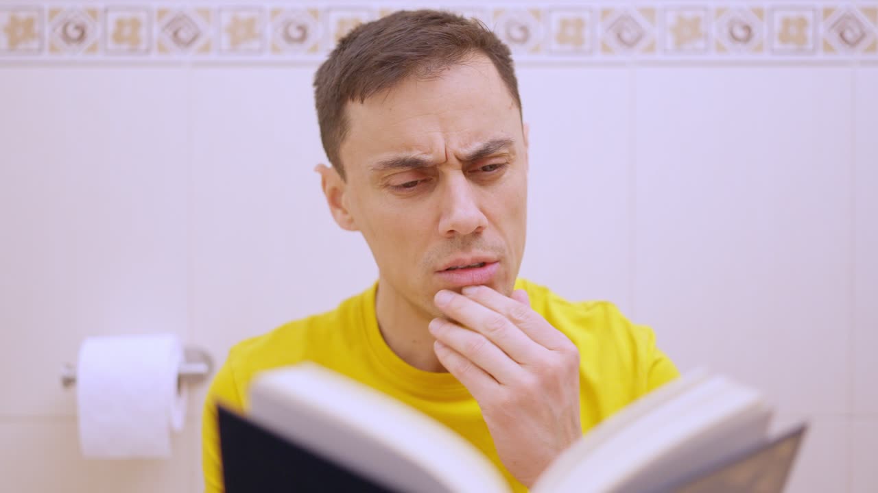 Homem lendo um livro no vaso sanitário
