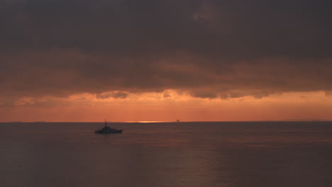 Wide-aerial-view-of-a-Royal-Navy-Warship-sailing-on-a-calm-sea-at-sunrise