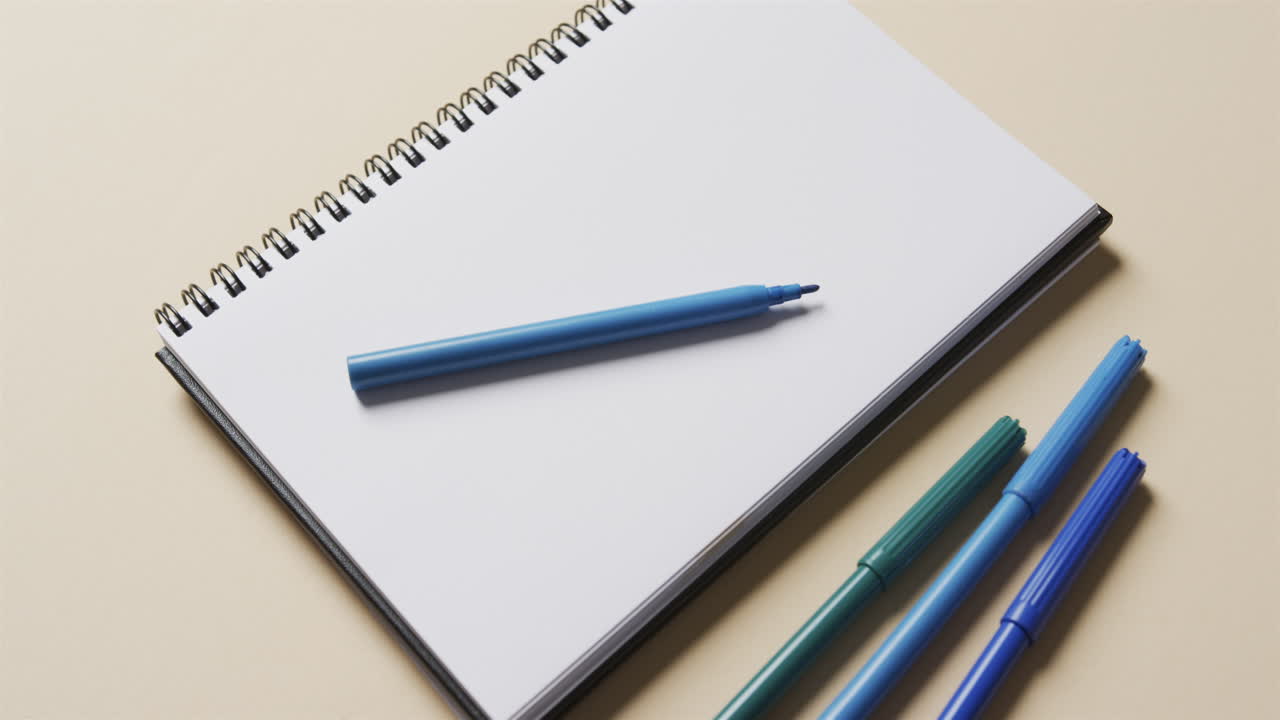 슬로우 모션으로 베이지색 배경에 파란색 마커를 가진 노트북의 클로즈업