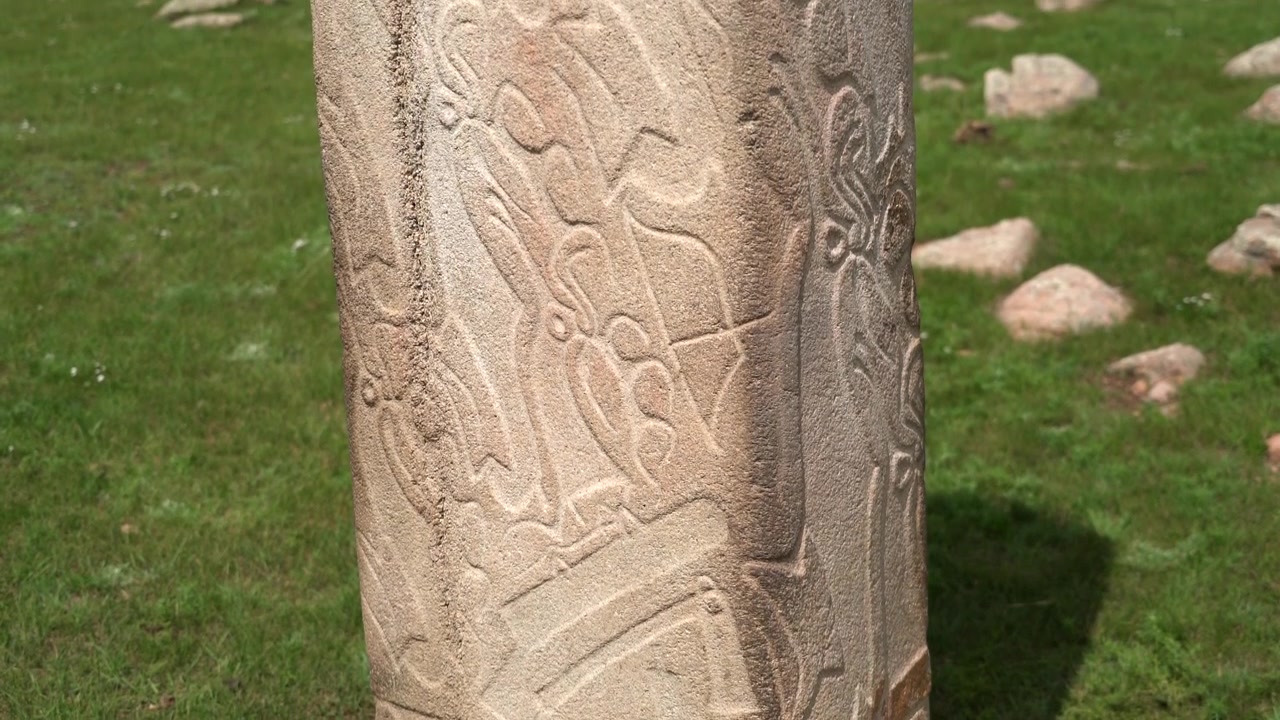 Antica stele di pietra con intagli intricati in un campo erboso
