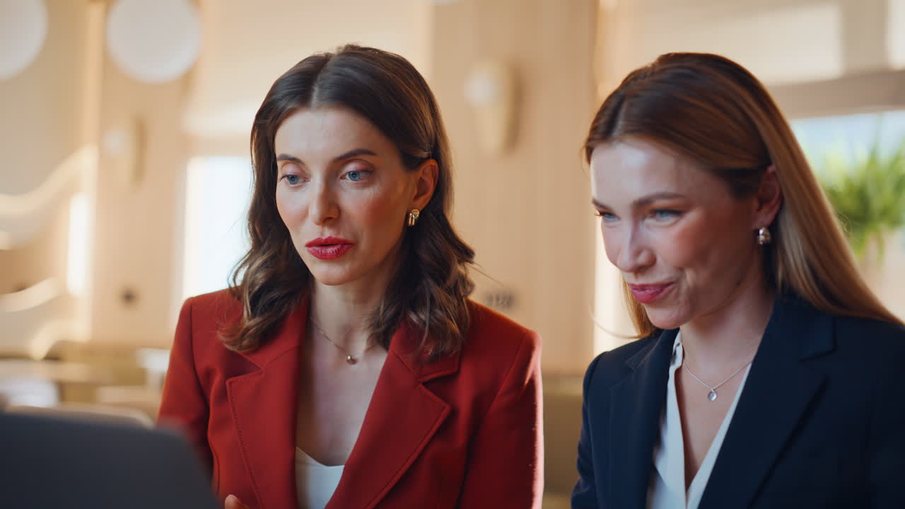 Smiling partners video calling by laptop sitting cafe closeup. Women talking