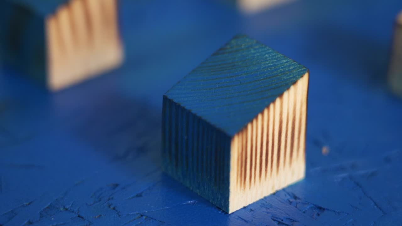 Spray painting a single wooden block blue, showing texture as paint is applied