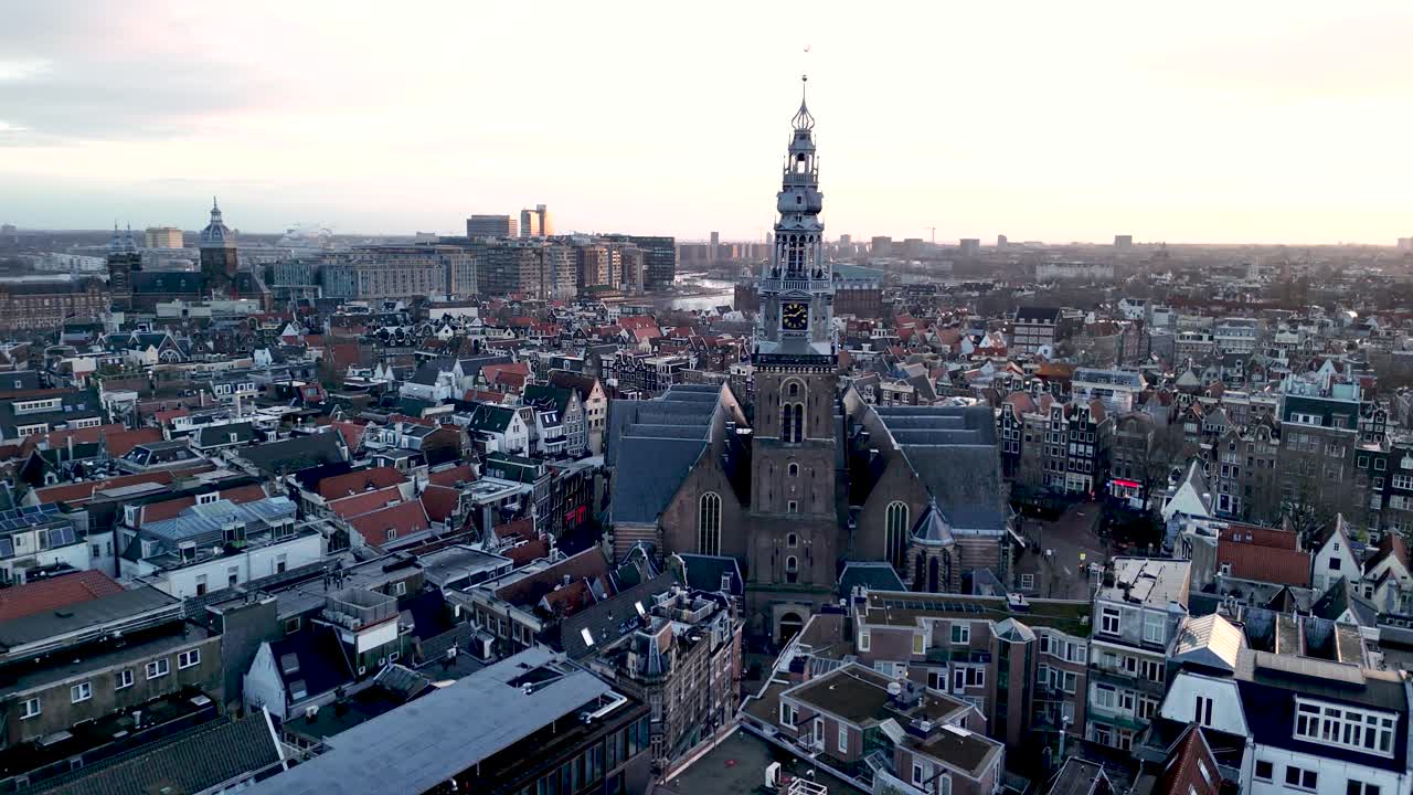 Stunning aerial view captures the charm of Amsterdam with its historic architecture as the sunset casts a golden glow. The city bustles below, showcasing its vibrant culture