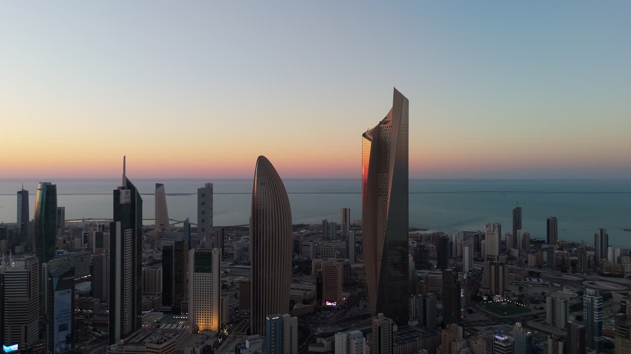 Breathtaking 4K drone footage of Kuwait City skyline at sunrise. Soft dawn light reveals iconic towers, roads, and coastline. Ideal for themes of growth, peace, and Gulf urbanism.