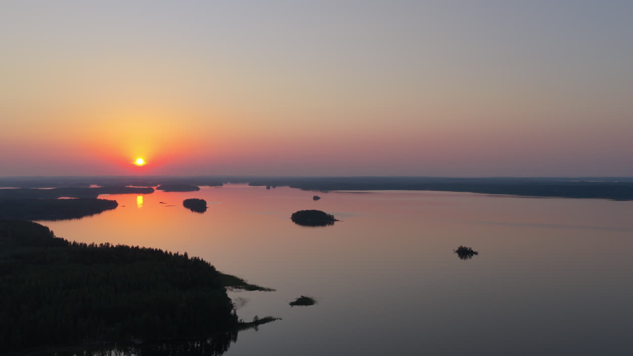 Aerial rising shot rotating over lake Saimaa, beautiful, summer sunset in Finland