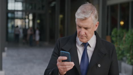 portrait successful senior businessman boss using smartphone smiling enjoying browsing online texting on mobile phone checking emails in city slow motion