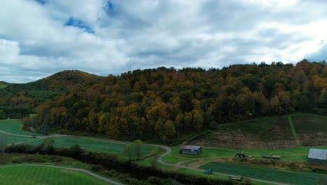 El-Tiempo-De-Los-Drones-Pasa-A-Lo-Largo-De-Una-Carretera-Sinuosa-En-El-Campo-Que-Corre-A-Lo-Largo-De-Un-Río-Y-Envuelve-Las-Montañas-Con-Hojas-Coloridas-Durante-El-Otoño