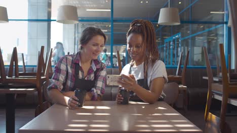 diversas camareras usando teléfonos inteligentes en un café vacío antes de abrir. en tiempo real