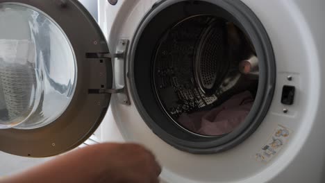 Woman-Doing-Laundry-Putting-Multiple-Colored-Clothing-And-Sheets-Into-Washing-Machine