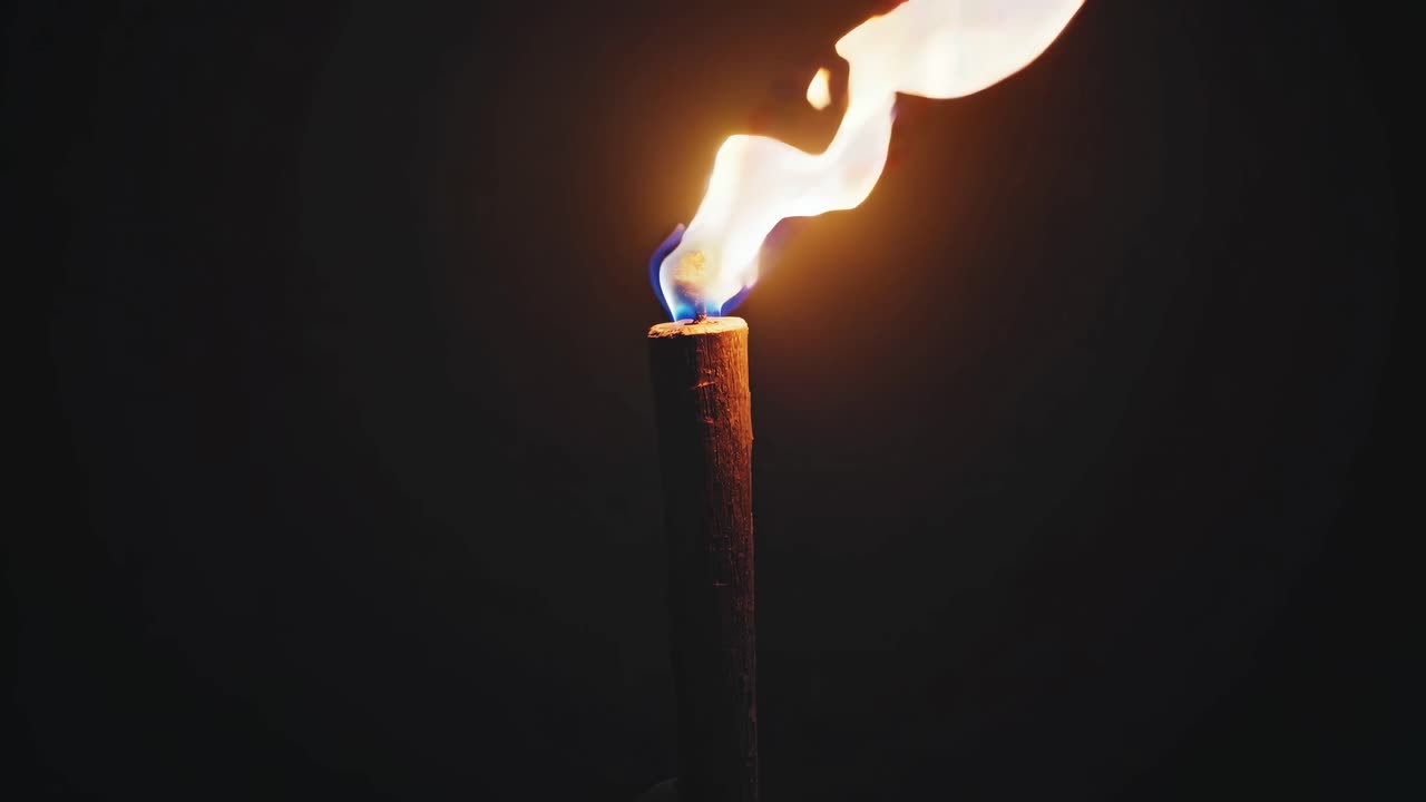 Eine dramatische Nahaufnahme eines Videos einer Fackel vor einem dunklen Hintergrund, die die flackernde Flamme einfängt