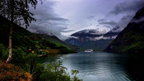 Flam,-Norway:-Timelapse-shot-of-a-giant-cruise-ship-in-motion-in-Norwegian-Fjord-in-Flam,-Norway-on-a-cloudy-day-with-dark-clouds-covering-the-mountain-peaks