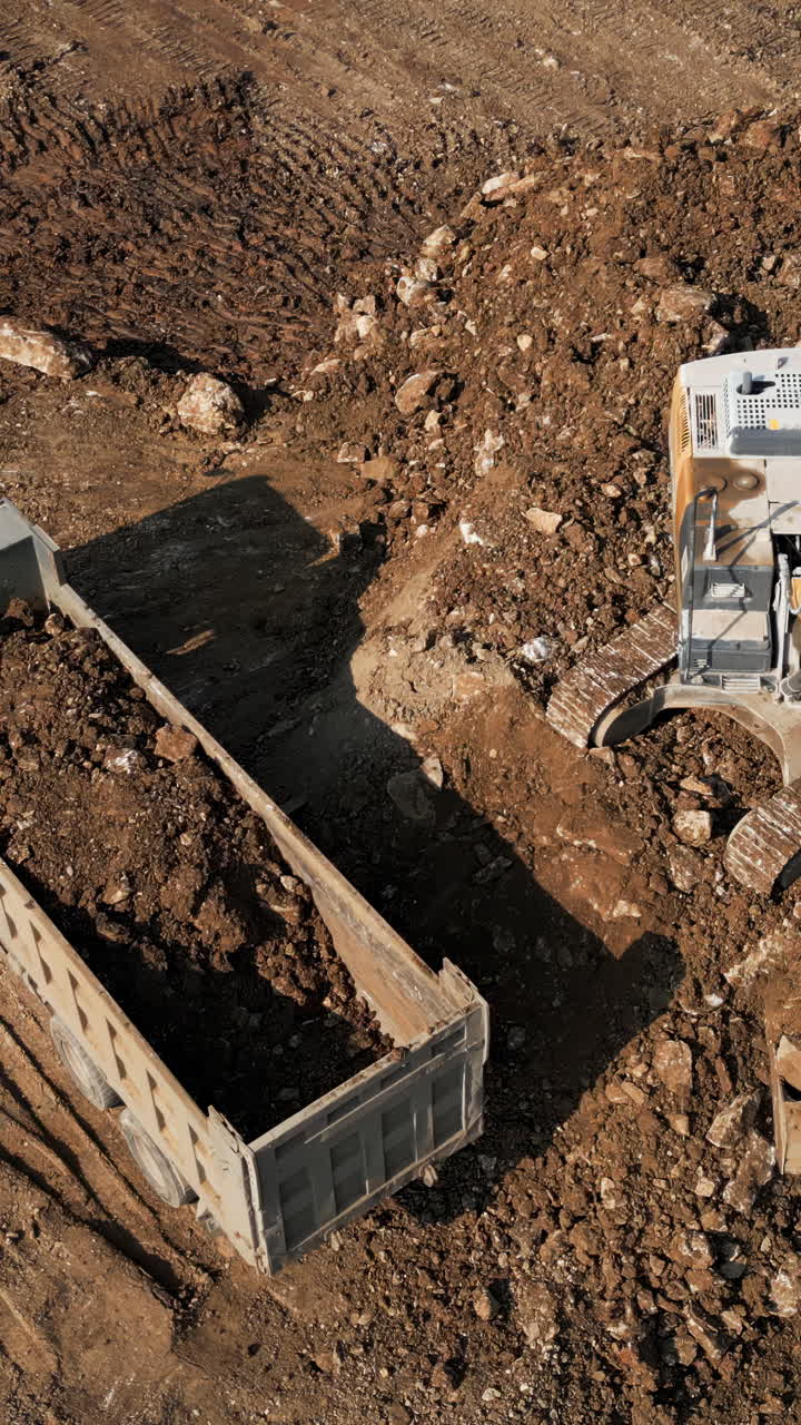 Excavator Digging and Loading Dirt into a Truck Trailer at a Construction Site