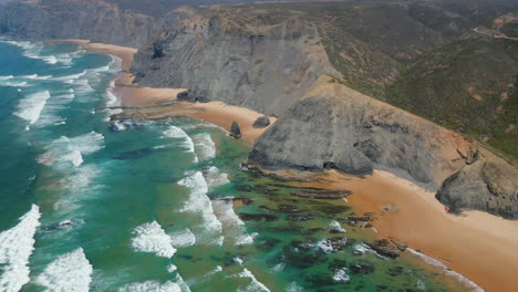 Vista-Aérea-De-La-Paradisíaca-Costa-Vicentina-Con-Acantilados-Junto-A-La-Playa-Y-Olas-Rompiendo-En-La-Orilla-En-Un-Soleado-Día-De-Verano,-Algarve,-Portugal