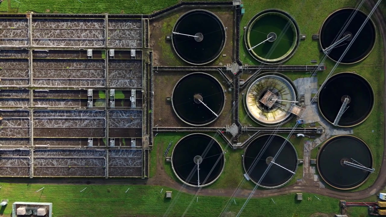 Drone view of industrial water treatment infrastructure and circular clarifying basins.