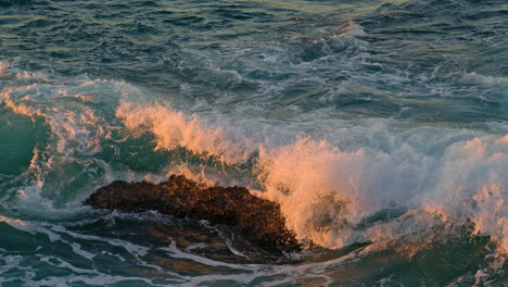 high waves rolling dark rocks in sunlight nature close up. ocean water breaking