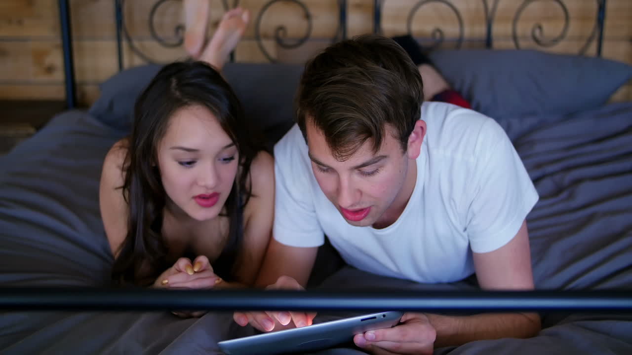 침실에서 디지털 태블릿을 사용하는 커플